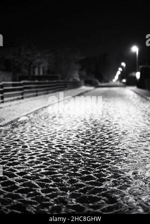 Photo sombre de la route pavée dans la nuit d'hiver. Banque D'Images