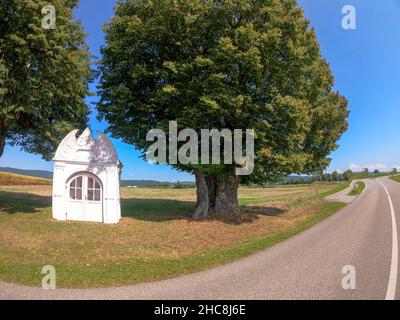 Belle photo d'une chapelle dans un endroit idyllique entre deux arbres sur le côté du chemin Banque D'Images