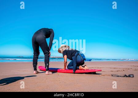 Un instructeur de sexe masculin démontre comment se lever à bord d'une planche de surf pour l'homme Banque D'Images