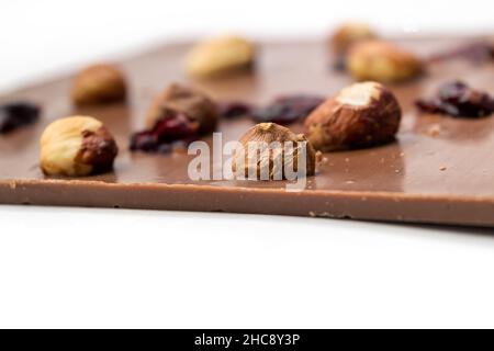 Chocolat au lait fait à la main avec noisettes, raisins secs et fruits secs sur fond blanc.Mise au point sélective Banque D'Images