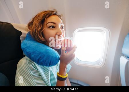 Une femme mange une collation saine aux fruits dans la cabine d'un avion - une pomme rouge mûre Banque D'Images