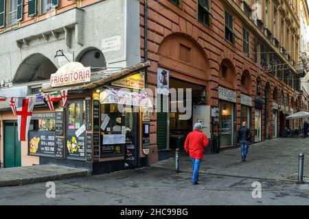 Aperçu du centre historique avec une vieille boutique de puces vendant des spécialités typiques de Gênes dans un coin de rue des arcades de Portici di Sottoripa, Gênes Banque D'Images