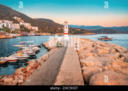 Vue charmante sur la station balnéaire de Kas en Turquie au coucher du soleil.Phare romantique à l'entrée du port et maisons blanches avec orang Banque D'Images
