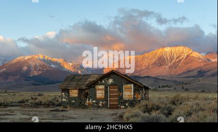 Ancien bâtiment abandonné au lever du soleil avec les montagnes de la Sierra Nevada au loin Banque D'Images