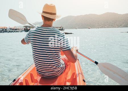 Un voyageur heureux kayaks à proximité d'un sarcophage ancien et d'un tombeau lycien dans la ville inondée de Kekova en Turquie.Des vacances agréables et saines Banque D'Images