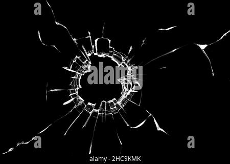 Effet photo de verre brisé, un trou avec des fissures dans le verre sur un fond sombre Banque D'Images