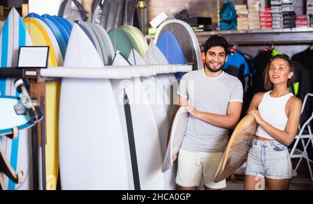 Couple d'homme positif avec des planches de surf dans la boutique Banque D'Images