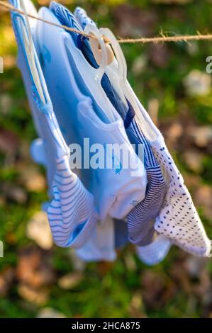 Plan vertical des vêtements d'un bébé suspendus sur une corde sur un fond flou Banque D'Images