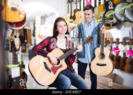 Adolescent choisissant la meilleure guitare acoustique Banque D'Images