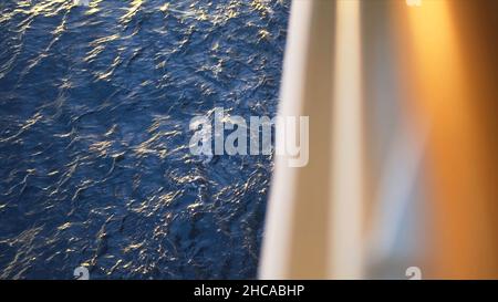 Surface de l'eau avec de petites vagues et le bord flou du bateau.Reflet du soleil sur la surface bleue de la mer. Banque D'Images