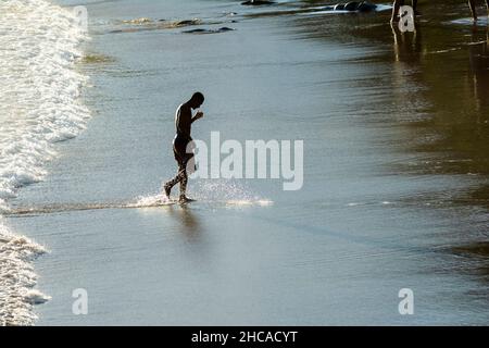 Homme sortant lentement de la mer de la plage d'Ondina après avoir été baigné.Salvador Bahia Brésil. Banque D'Images