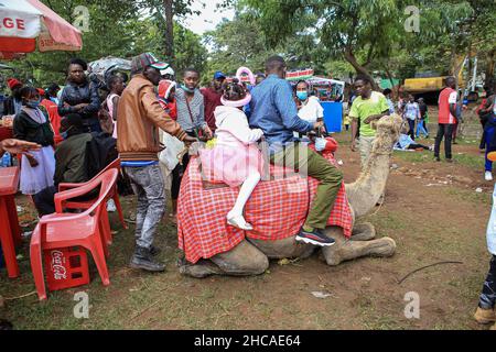 Nairobi, Kenya.25th décembre 2021.Un père et une fille qui vont faire une balade à dos de chameau, le jour de Noël.Pendant de nombreuses années, les Kenyans vivant à Nairobi et ses environs passent le jour de Noël dans les parcs d'Uhuru et Central.Toutefois, ce n'est pas le cas cette année, car les deux parcs restent fermés pour rénovations.Cela ne les a pas empêcher de profiter de la journée dans de petits espaces disponibles.Crédit : SOPA Images Limited/Alamy Live News Banque D'Images