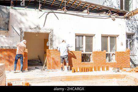 Deux ouvriers posant des briques sur un nouveau mur sur un site de construction de maison à Almaty, Kazakhstan Banque D'Images