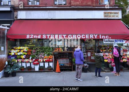 New York, NY - 15 novembre 2021 : les clients se trouvent à l'extérieur d'une épicerie locale à l'ancienne avec des fleurs en plein air colorées Banque D'Images