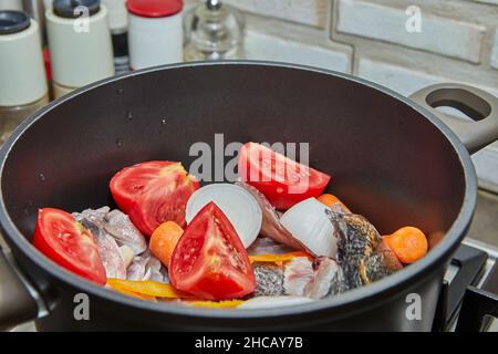 La perche de poisson est voncée dans le chou-fleur avec des tomates, des carottes et des oignons sur le poêle à gaz.Gros plan Banque D'Images
