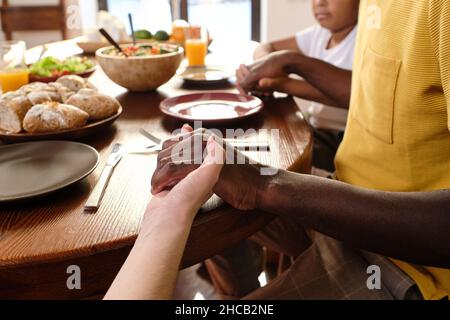 Les mains de l'homme africain, de sa femme caucasienne et de leur fils pendant prier à table avant de dîner ou de petit déjeuner Banque D'Images