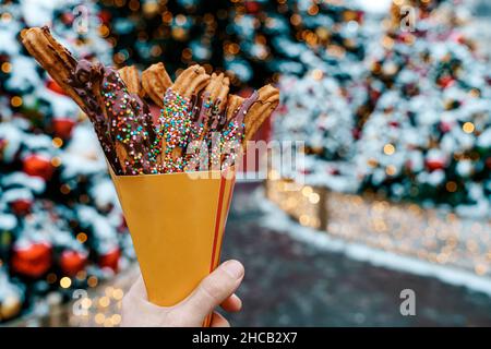 Gaufres churos dans la main sur le marché de la neige d'hiver.Churros cuisine mexicaine de rue dessert.Bonbons fast-food, biscuits de Noël.Photo de haute qualité Banque D'Images