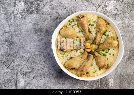 Pilons de poulet à une casserole avec riz dans un plat blanc sur fond gris foncé.Vue de dessus, plan d'appartement Banque D'Images