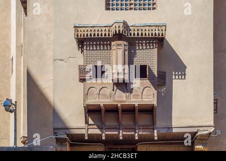 Fenêtre d'oriel de style de l'époque Mamluk recouverte d'une grille en bois entrelacée - Mashrabiya, sur un mur extérieur de grunge sorbrée, à la Maison historique de l'architecture égyptienne, vieux Caire, Egypte Banque D'Images