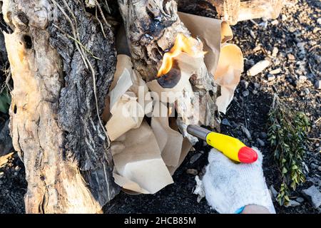 éclairage du feu avec une torche en papier et butane à l'extérieur par beau temps Banque D'Images