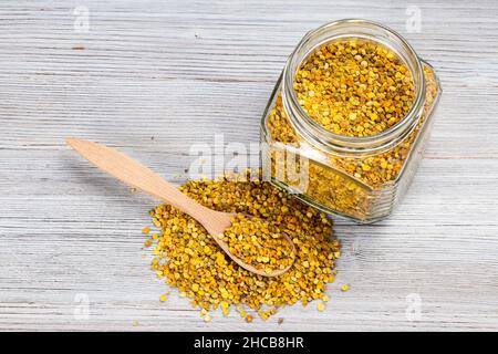 au-dessus de la vue du pot en verre et de la cuillère dans un tas de pollen d'abeille naturel sur un panneau en bois gris Banque D'Images