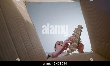 Photo d'une femme qui lance un conteneur en carton, vue de dessous Banque D'Images