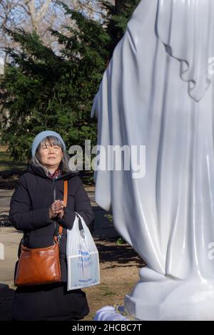 Après un service de prière dans un parc, dévoter catholique romain prie une statue de la Vierge Marie.Sur le site des apparitions de Veronica Lueken à New York. Banque D'Images