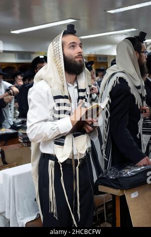 Un juif orthodoxe dans la prière semble regarder vers Dieu.Dans une synagogue de Brooklyn, New York. Banque D'Images