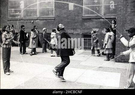 Une jeune fille fait une double corde de saut hollandais dans un cours d'école à Brooklyn, New York en 1981. Banque D'Images