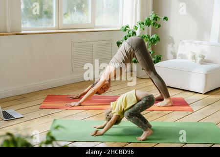 Jeune fille pratiquant la pose de yoga avec une femme à la maison Banque D'Images