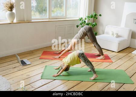Mère et fille faisant face à la posture du chien vers le bas à la maison Banque D'Images