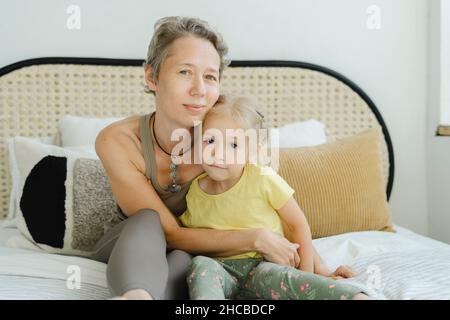 Mère assise avec fille sur le lit à la maison Banque D'Images