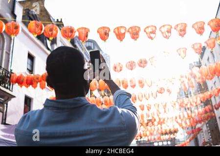 Homme photographiant des lanternes chinoises à travers un smartphone dans China Town Banque D'Images
