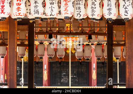 Vue à travers la scène ouverte de la salle Buden avec rangée de lanternes en papier blanc, chochin, pendante, à la salle principale du sanctuaire de Yaasaka à Kyoto. Banque D'Images