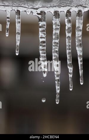 Des glaçons s'écoulant d'un toit en hiver. Banque D'Images