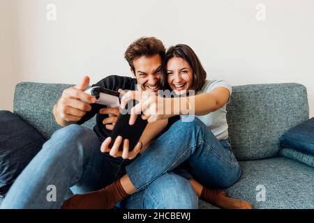 Joyeux petit ami et ami jouant à un jeu vidéo avec une manette à la maison Banque D'Images