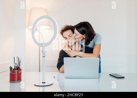 Jeune petite amie embrassant homme travaillant dans le bureau à domicile Banque D'Images