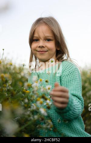 Fille souriante debout près de fleurs dans la prairie Banque D'Images