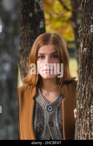 Jeune femme vue à travers le tronc d'arbre dans le parc Banque D'Images