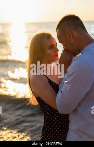 Homme tenant et embrassant la main de la femme au coucher du soleil Banque D'Images