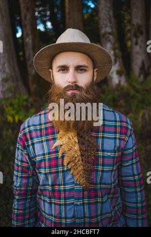 Jeune homme hippster avec des feuilles sèches sous la barbe dans la forêt Banque D'Images