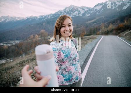 Femme donnant un contenant à boisson isolé à un ami sur la montagne Banque D'Images