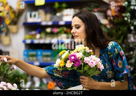 Photo avec foyer sélectif d'une femme de beauté tenant un seau de fleurs dans un magasin de fleuriste Banque D'Images