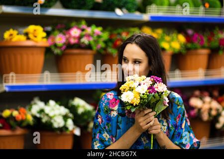 Portrait avec un accent sélectif sur une femme souriante tenant un seau de fleurs dans un fleuriste Banque D'Images