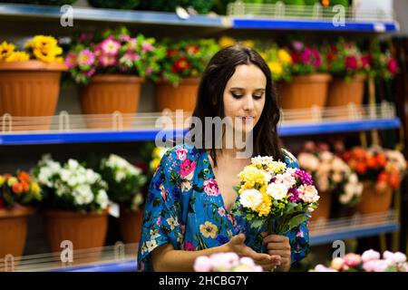 Portrait avec un accent sélectif sur une femme tenant un seau de fleurs dans un magasin de fleuriste Banque D'Images