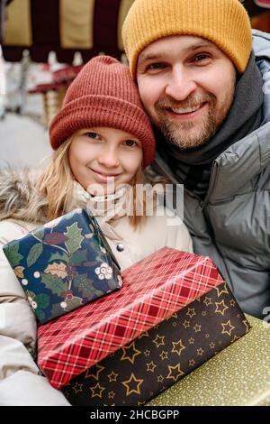 Père et fille tenant des cadeaux de Noël devant le magasin Banque D'Images