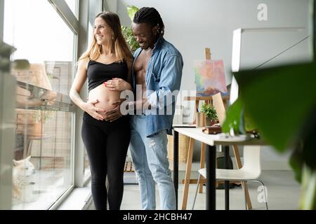 Homme et femme enceinte touchant le ventre à la maison Banque D'Images