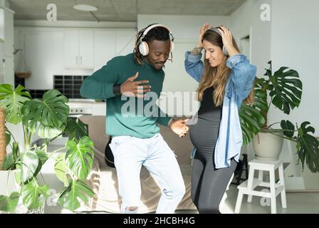 Femme enceinte avec un homme portant un casque dansant à la maison Banque D'Images