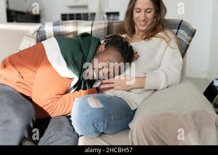 Rire homme assis par une femme enceinte tenant une tablette numérique dans le salon Banque D'Images