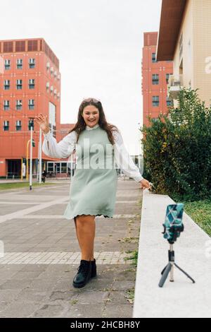 Jeune femme aux courbes qui enregistre des vidéos tout en vlogging sur un smartphone Banque D'Images